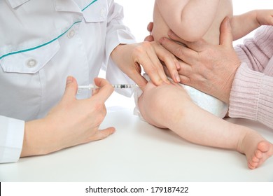 Doctors hand with syringe vaccinating child baby flu injection shot in leg isolated on a white background