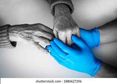 Doctor's Hands In A Blue Gloves Holds The Hands Of An Elderly Woman, A Patient. Handshake, Caring, Trust And Support. Medicine And Healthcare.