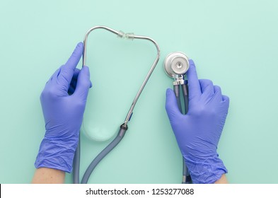 Doctor's hands in blue gloves with stethoscope on mint background.Medical concept. Top view. Flat lay.