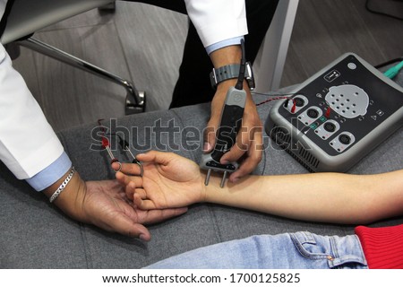 
doctor's hands conducting electromyography study and nerve conduction in young woman