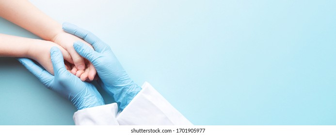 Doctor's hands in gloves holding child's hands. Medical banner with copy space on blue background. Care concept.