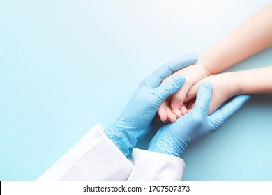 Doctor's hands in gloves holding child's hands. Medical care concept.