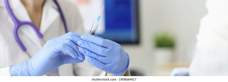 Doctor's hands hold syringe with needle next to the patient. Medical assistance concept