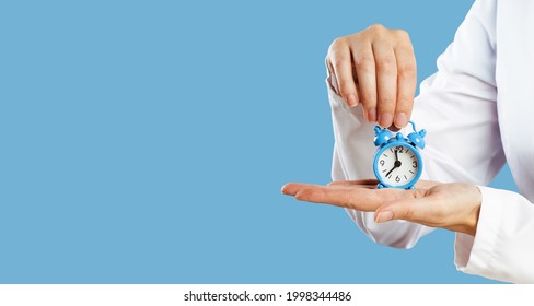 Doctors Hands Holding Blue Alarm Clock Over Blue Background. Time Is Crucial Life Saver. Medical Banner. Copy Space. Book Appointment Or Checkup Time Reminder. Schedule. Opening Hours Deadline