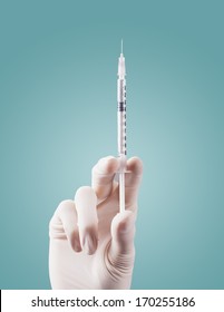 Doctor's hands holding syringe closeup on green background