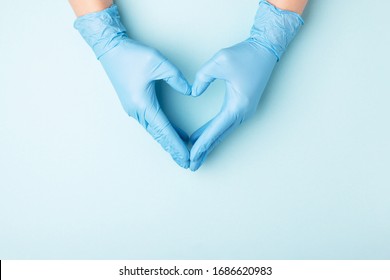 Las manos del médico en guantes médicos en forma de corazón sobre fondo azul con espacio para copiar.