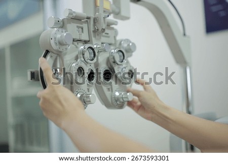 The doctor's hands are operating medical instruments. The doctor's hand is using a machine to measure the patient's eyesight.