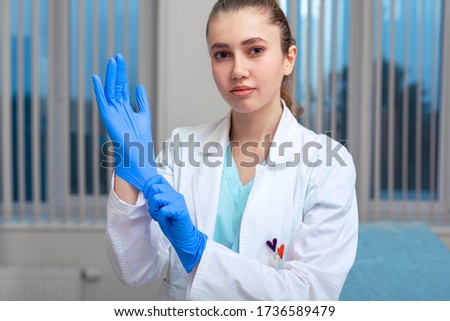 Doctor's hands putting on latex gloves in a hospital. Woman in a doctor's smock in latex gloves. Protection against virus and bacteria. Kovid 19. Health