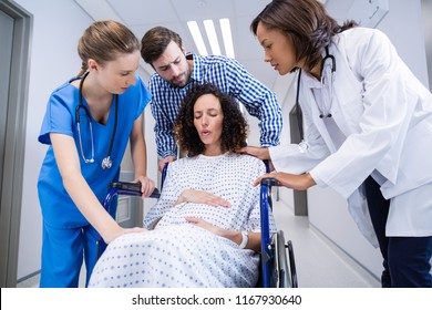 Doctors and man comforting pregnant woman in corridor of hospital - Powered by Shutterstock