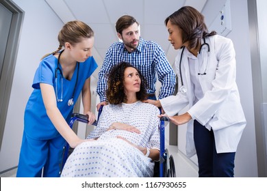 Doctors and man comforting pregnant woman in corridor of hospital - Powered by Shutterstock