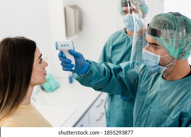 Doctors measuring fever to a young patient during coronavirus pandemic time - Medical team staff screening people for Covid 19 disease - Focus on right worker hand - Shutterstock ID 1855293877