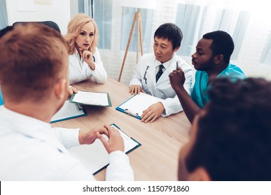 Doctors Meeting. Diagnostic Discussion. Multinational Medicals. Professional Consultation. Patient's Test Results. Young Specialists. Clinician Team Group. Sitting Interns. Surgeon Assistants.