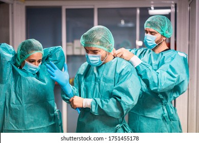 Doctors and nurse preparing to work in hospital for surgical operation during coronavirus pandemic outbreak - Medical workers getting dressed inside clinic - Focus on center man face