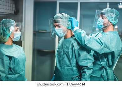 Doctors and nurse preparing to work in hospital for surgical operation during coronavirus pandemic outbreak - Medical workers getting dressed inside clinic - Focus on left men faces
