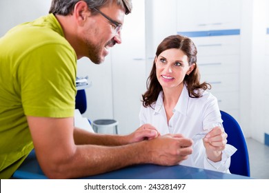 Doctors Nurse With Telephone In Front Desk Making Appointment With Patient