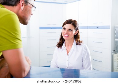 Doctors Nurse With Telephone In Front Desk Making Appointment With Patient