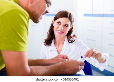 Doctors Nurse With Telephone In Front Desk Making Appointment With Patient