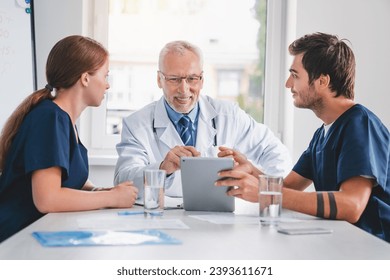 Doctors and nurses looking at digital tablet during medic meeting in hospital. Medical team workers browsing treatment, giving online prescriptions. Telemedicine concept - Powered by Shutterstock