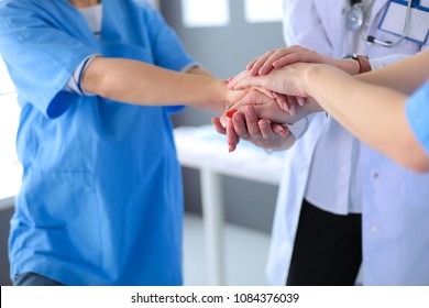 Doctors and nurses in a medical team stacking hands - Shutterstock ID 1084376039