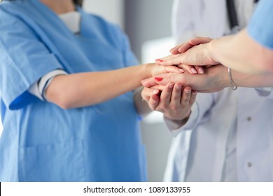 Doctors and nurses in a medical team stacking hands - Shutterstock ID 1089133955
