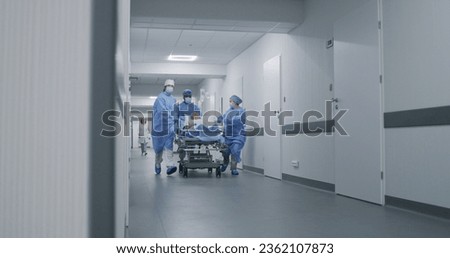 Doctors, nurses and paramedics run and push stretcher with seriously injured patient to operation room. Medical staff save human life in emergency department. Medical facility corridor. Slow motion. ストックフォト © 