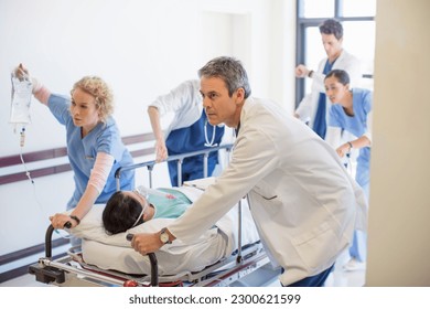 Doctors and nurses rushing patient on stretcher down hospital corridor - Powered by Shutterstock