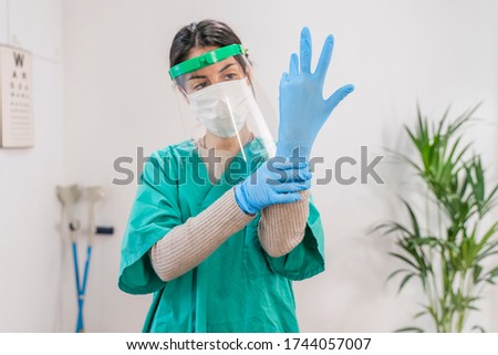 Doctors and nurses working in the hospitals and fighting the coronavirus. Doctors are heroes. Female nurse in the protective suits and masks putting on rubber gloves. Sanitary cleaner. 
