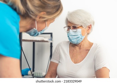 At The Doctor's Office - An Old, Retired Lady Smiling Sincerely At Her Doctor While Wearing Face Mask During A Medical Checkup. High-quality Photo