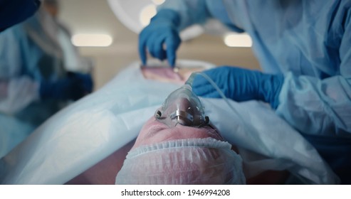 Doctors Performing Surgery While Patient Lying On Operating Table. Surgeon In Gloves Doing Scalpel Incision Performing Surgery In Operating Room. Concept Of Medicine And Healthcare