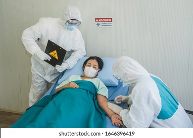 Doctors In Personal Protective Equipment Collecting Blood From A Infected Female Patient In The Control Area. Coronavirus COVID 19 Quarantine Area