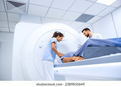 Doctors preparing patient for full body scanning procedure inside MRI diagnostic center.