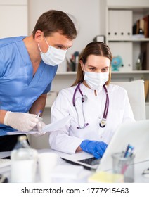 Doctors In Protective Medical Masks Enter Patient Data Into The Clinic Computer Network