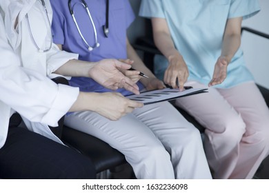 Doctors Reviewing Medical Chart In Hospital