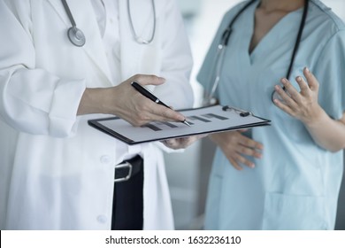 Doctors Reviewing Medical Chart In Hospital