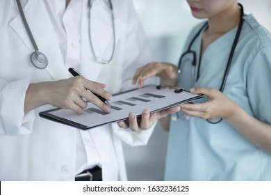 Doctors Reviewing Medical Chart In Hospital