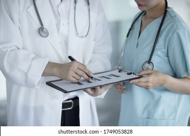 Doctors Reviewing Medical Chart In Hospital