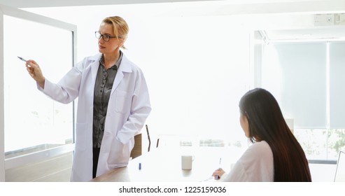 Doctors or scientists are teaching and explaining students and patients writing on board 