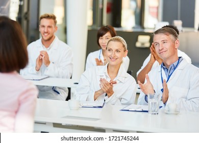 Doctors in a seminar on medical education clap applause for the speaker