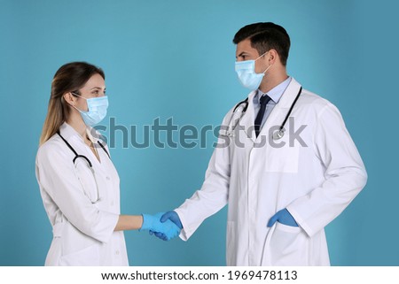 Doctors shaking hands on light blue background