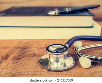 Doctors Stethoscope On Wooden Background With Text Book For Medical Concept In Vintage Style.