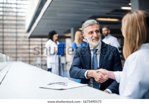 Doctors talking to pharmaceutical sales\
representative, shaking\
hands.