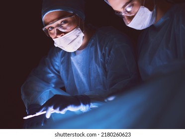 Doctors team in surgery in a dark background. - Powered by Shutterstock