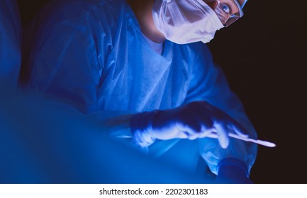 Doctors Team In Surgery In A Dark Background.