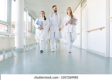 Doctors, two women and a man, in hospital walking down the corridor - Powered by Shutterstock