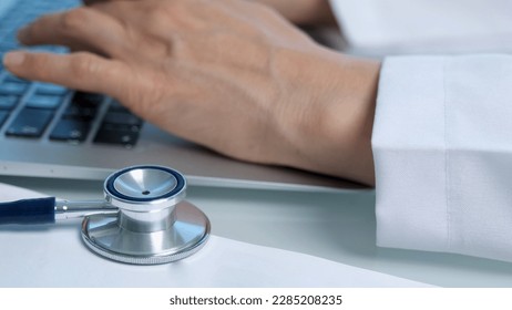 Doctor's typing prescriptions or drugs to patient digitally using a laptop with stethoscope - Powered by Shutterstock