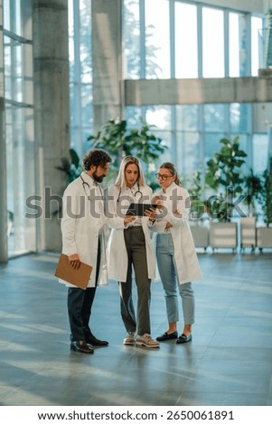 Doctors using digital tablet, discussing patient diagnosis and treatment plan in modern hospital lobby