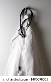 A Doctors White Lab Coat Hanging On A Hook With Stethoscope.