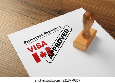 Document with approved permanent residency visa in Canada and stamp on wooden table - Shutterstock ID 2218779839