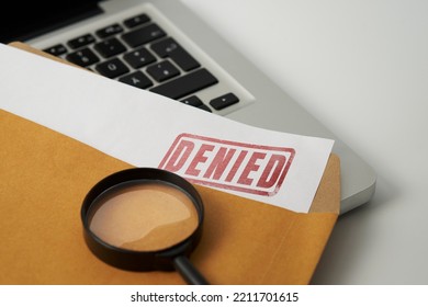 Document with denied stamp and magnifying glasses put on the laptop on wooden table, - Shutterstock ID 2211701615