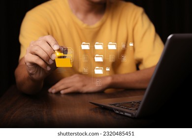 Document Management System (DMS) being setup by IT consultant working on laptop computer in office with document directory. Software for archiving, searching and managing corporate file information